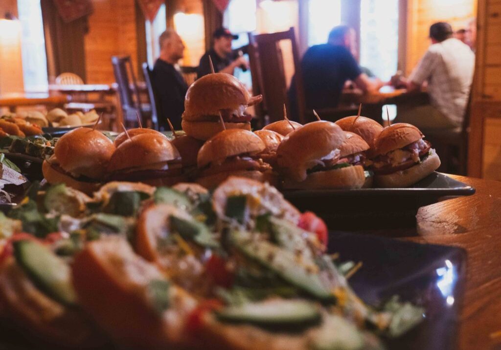 Assorted sliders with people dining in background